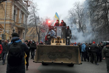 Unos manifestantes van montados encima de una excavadora con dirección a los muros policiales que estan frente al edificio de administración presidencial. AP / Kiev, Ucrania