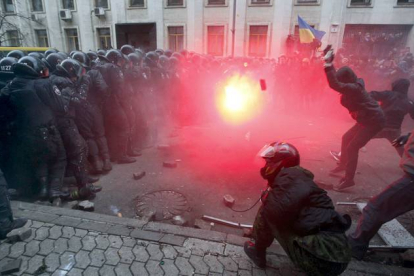 Los manifestantes lanzan un artefacto incendiario al muro que la policía ha hecho frente al edificio de administración presidencial. EFE / Kiev