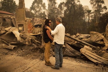 Dos personas ante las ruinas de un edificio arrasado por las llamas.