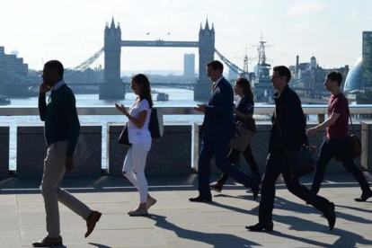 Varios transeúntes se dirigen a la City cruzando el puente de Londres, frente al puente de la Torre de Londres, el 24 de junio.