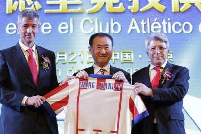 Wang Jianlin, presidente del grupo Wanda, sostiene una camiseta del Atlético de Madrid entre el director general, Miguel Ángel Gil, y el presidente, Enrique Cerezo, tras comprar un 20% del club por 45 millones de euros.