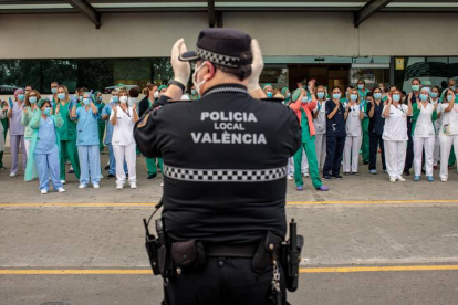 Un policía local y sanitarios del Hospital La Fe de Valencia, durante el aplauso diario. BIEL ALIÑO