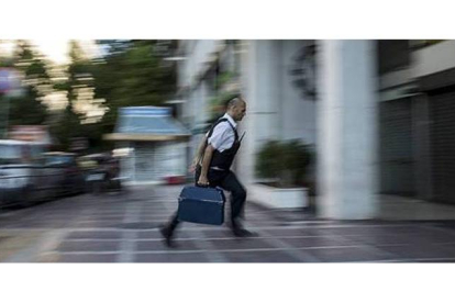 Un hombre entra dinero con una maleta en una sucursal bancaria de la ciudad de Atenas. MARKO DJURICA / REUTERS