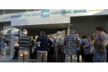 Ciudadanos griegos hacen cola en una sucursal del National Bank de Grecia a la espera de sacar su dinero.  ORESTIS PANAGIOTOU / EFE