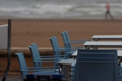Sillas y mesas en la playa de la Malvarrosa de Valencia, donde un turista practica deporte. KAI FÖRSTERLING