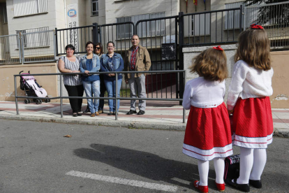 Dos pequeñas que acuden al comedor del Antonio Valbuena posan en el colegio con un grupo de madres y padres