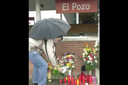 Un ciudadano coloca un ramo de flores y una vela en las puertas de acceso a la madrileña estación de El Pozo
