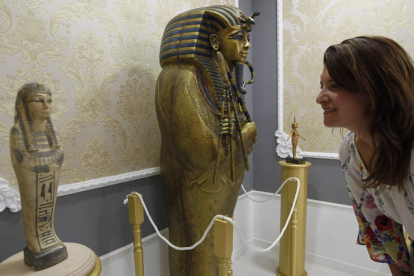 Una mujer contempla una pieza del Museo-Liceo Egipcio; a la derecha, la réplica del sarcófago de Tutankamon.