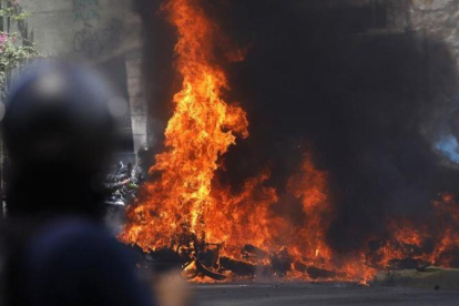 Varios vehículos en llamas tras enfrentamientos entre manifestantes y policías en Venezuela.
