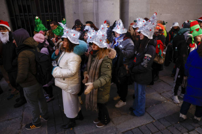 Varias personas hacen cola este viernes ante el Teatro Real de Madrid para asistir al sorteo extraordinario de Navidad de la Lotería Nacional y ver en directo a los niños de San Ildefonso repartir 2.500 millones de euros. EFE/  J. J. GUILLÉN