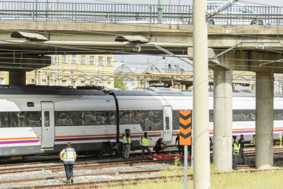 Agentes del Cuerpo Nacional de Policía y de seguridad de Renfe junto al cuerpo de una persona que ha sido hallado este lunes entre dos vagones de un tren en la estación de Santa Justa de Sevilla. RAÚL CARRO