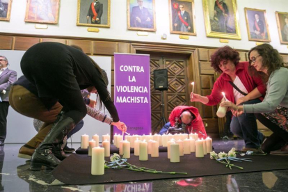 Asistentes al acto de homenaje a las víctimas de la violencia machista que se ha celebrado hoy en el consistorio zaragozano, encienden unas velas.