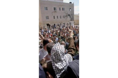 Arafat hace la señal de la victoria. Al fondo, el boquete en su dormitorio
