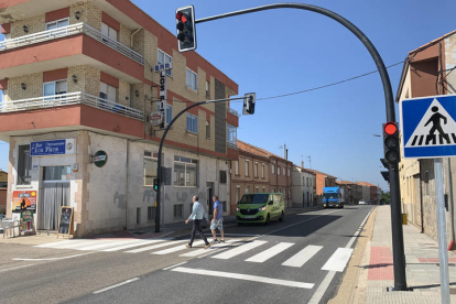 Unos peatones hacen uso del semáforo en San Martín del Camino. DL