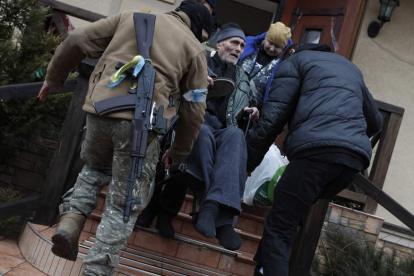 Personal de Defensa Territorial de Ucrania ayuda a evacuar a las personas mayores de un refugio en la ciudad de Irpin. ATEF SAFADI