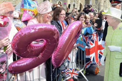 La reina Isabel saluda este jueves al público que la ha esperado junto al castillo de Windsor para felicitarla por su 90º aniversario.