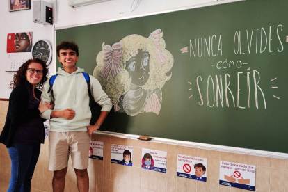 El artista más joven del proyecto con unos de sus dibujos y la tutora del aula de Maristas