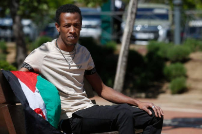 Mohamed Salek Abeid posa con la bandera saharaui en un banco de un parque de León. FERNANDO OTERO