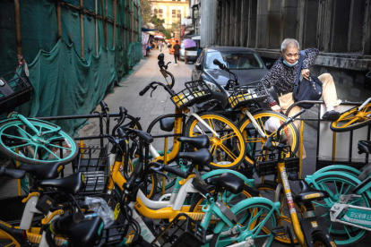 Un hombre salta una barricada de bicicletas en Guangzhou en una zona no descontaminada. ALEX PLAVEVSKI