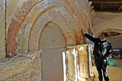 El párroco de San Pedro de Foncollada, Rubén Lorca, ante la portada románica ahora descubierta tras unas obras vecinales de mejora y saneamiento.