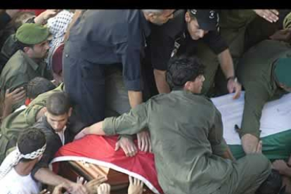 Varios guardias tratan de sujetar el féretro de Arafat, montado sobre un coche, intentado que no se cayera al suelo en el trayecto.