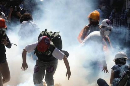 Manifestantes turcos corriendo para protegerse del gas lacrimógeno.