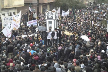 Miles de manifestantes llevan los ataúdes de los rebeldes asesinados en baba Amro, cerca de Homs (Siria).