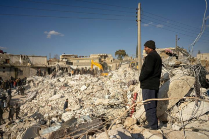 Un hombre observa cómo rescatistas y voluntarios buscan sobrevivientes bajo los escombros de casas derrumbadas, en la localidad de Harim, cerca de Idlib, Siria, el 8 de febrero de 2023. EFE EPA KARAM AL-MASRI