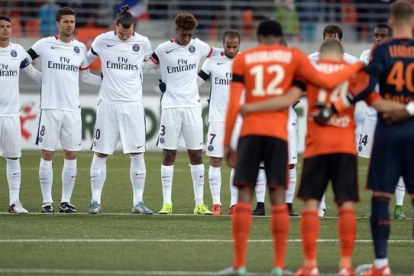 Los jugadores del PSG y del Lorient, durante el minuto de silencio previo al partido