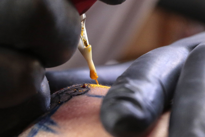 El tatuador leonés del All Street Barber & Tattoo Studio, Víctor Colado, durante la realización de un tatuaje de temática leonesa. CAMPILLO/ICAL