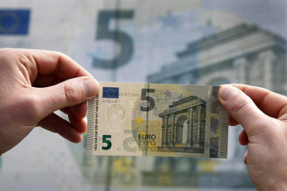 Un comprador, con un billete de cinco euros. EFE