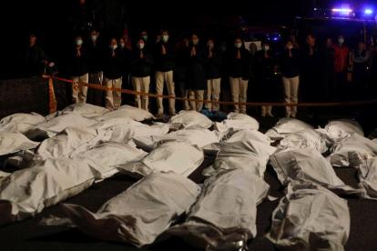 Voluntarios rezan ante los cadáveres de los fallecidos en el accidente de autobús en Taiwán.
