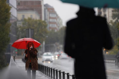 Dos transeúntes caminan entre la lluvia por las calles del centro de Madrid. MARISCAL
