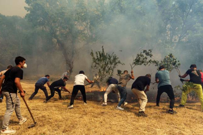 Vecinos de Villarejo apagan ayer un foco del incendio que se declaró el sábado. RAÚL SANCHIDRIÁN