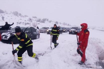 Unos militares tratan de liberar con palas los coches atrapados en la AP-6 por la nevada.