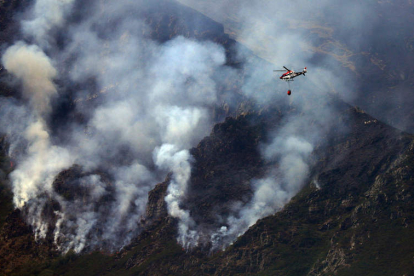 Un helicóptero se aproximaba ayer a la zona de Peñalba de Santiago donde la orografía hacía imposible el trabajo de las cuadrillas de tierra. ANA F. BARREDO