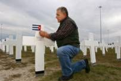 Un hombre coloca una bandera cubana en la cruz de su padre