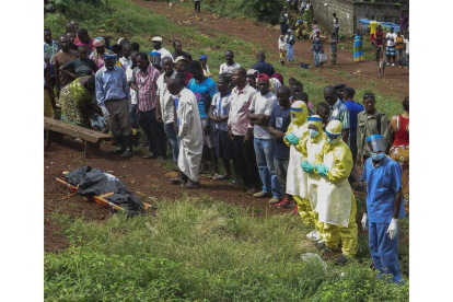 Unas personas rezan frente al cadáver de una víctima del ébola en Freetown, Sierra Leona.