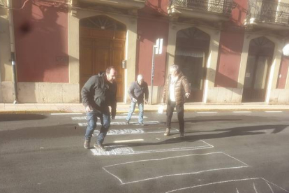 Un grupo de vecinos de Cistierna pintando con tizas los pasos de peatones. CAMPOS