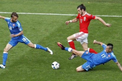 Bale conduce el balón perseguido por dos rivales en el partido inaugural de Gales.