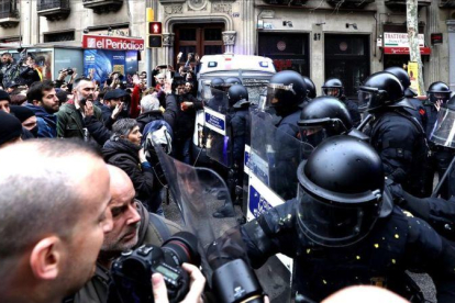 Manifestantes forcejean con mossos ante la Delegación del Gobierno en Cataluña.
