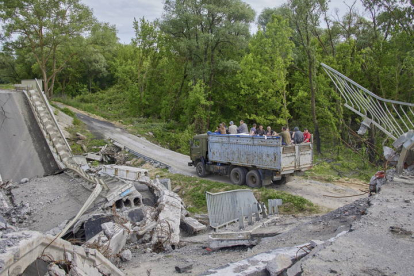Ucranianos cruzan bajo un puente destrozado en la zona de Kharkiv, en Ucrania. SERGEY KOZLOV