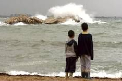 Dos niños observan las fuertes olas que el temporal levantó en L'Escala en Gerona
