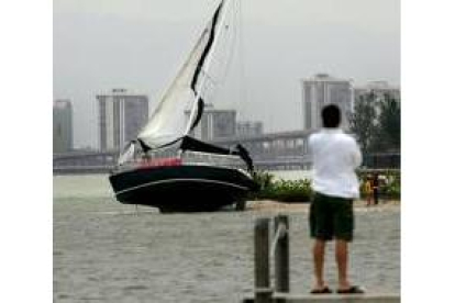 Un hombre observa un bote encallado en Key Biscayne, Miami