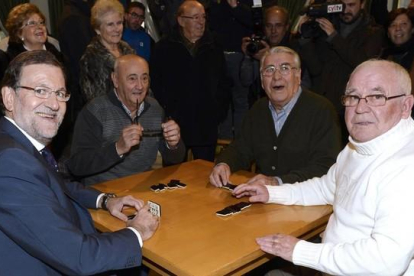 El presidente del Gobierno, Mariano Rajoy, junto a sus compañeros de juego en el Hogar del Pensionista, tras su intervención hoy en un mitin en la localidad vallisoletana de Olmedo.