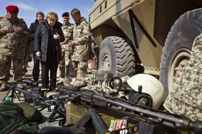 Angela Merkel observa varias piezas de armamento en su visita a Afganistán.