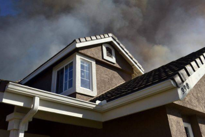 Una columna de humo emerge tras una casa en San Marcos, condado de San Diego (California).