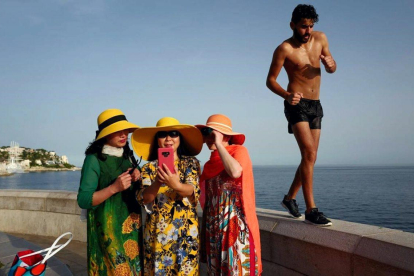 Un hombre pasa junto a unas turistas que se hacen una foto en Niza, Francia. / VALERY HACHE (AFP)