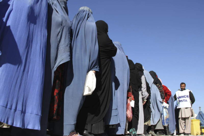 Mujeres afganas hacen una larga cola en un campo de refugiados para obtener alimentos.