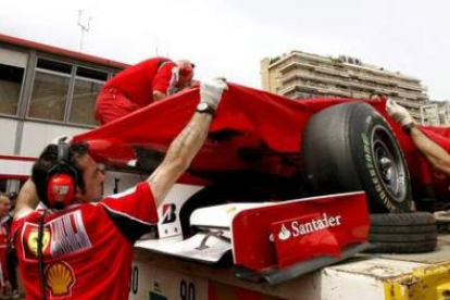 Una grúa retira el monoplaza de Alonso despues de que sufriera un golpe en el chasis.